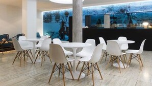 A modern interior with round tables and white chairs, a large pillar, and a mural on the wall.