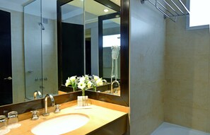 A bathroom with a large mirror, a sink, and a shower.