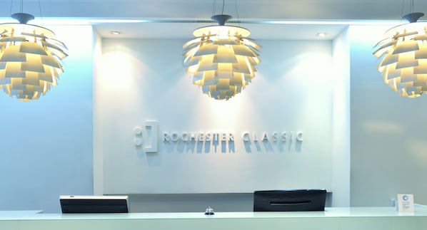 A reception desk with three hanging lamps and a sign reading "ROCHESTER CLASSIC".