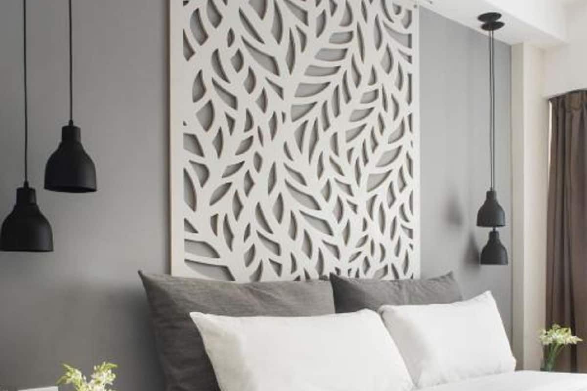 Une chambre moderne avec un grand lit, un panneau décoratif au mur et deux tables de chevet avec des lampes.