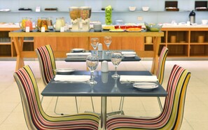 A dining area with a table set for four, striped chairs, and a buffet in the background.