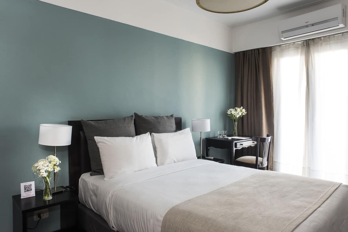 Une chambre d’hôtel avec un lit, des tables de chevet, un bureau et une chaise.