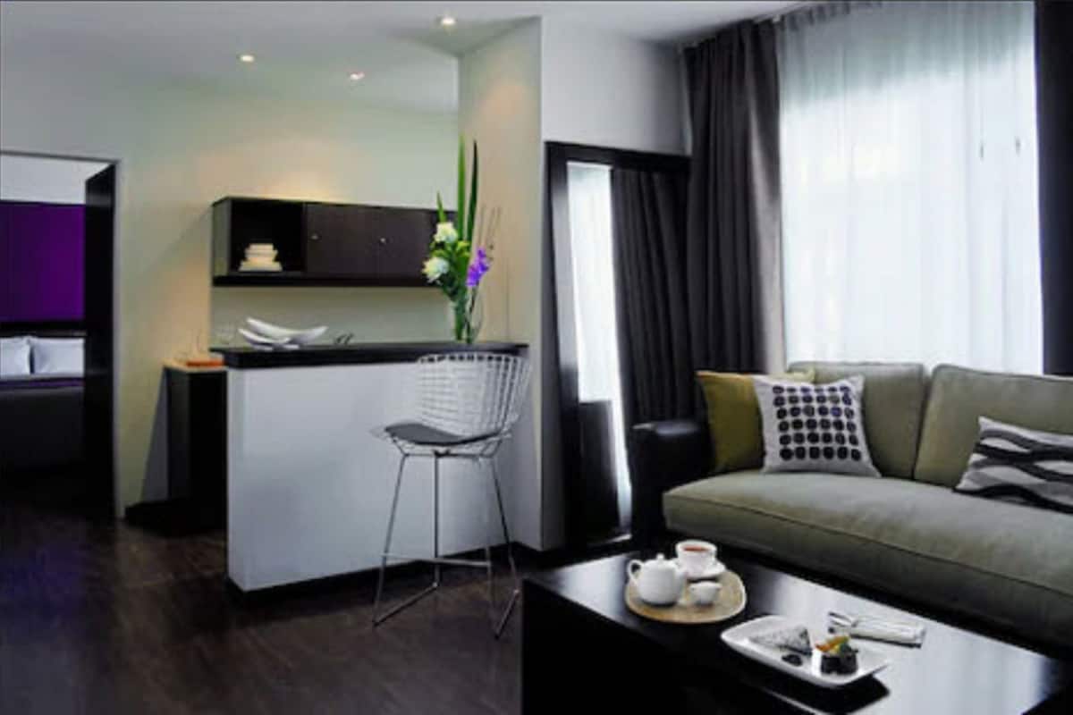 Une chambre d’hôtel moderne dotée d’une kitchenette, d’un coin repas et d’un espace de vie comprenant un canapé et une table basse.