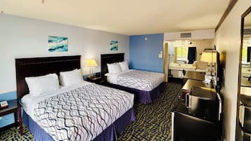 A hotel room with two beds, a desk with a mirror, and a bathroom with a sink and mirror.
