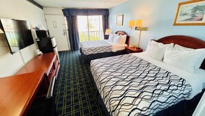 A hotel room with two beds, a desk, a television, and a window with curtains. - Hospitality Inn (North Platte)