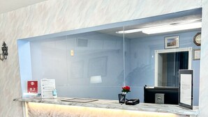 A reception desk with a marble counter, a clock, and a framed picture on the wall. - Hospitality Inn (North Platte)