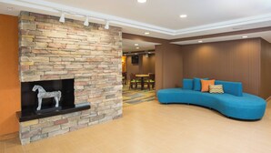 Een moderne lobby met een stenen openhaard, een blauwe bank en een houten wand.