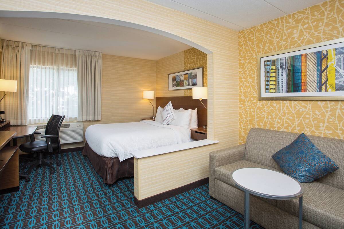 Une chambre d’hôtel comprenant un lit, un bureau, une chaise, un canapé et une petite table.