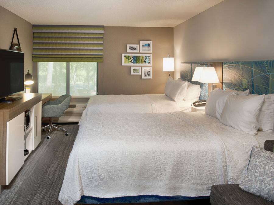 Een hotelkamer met een groot bed, een bureau met een computer, een stoel en een televisie.