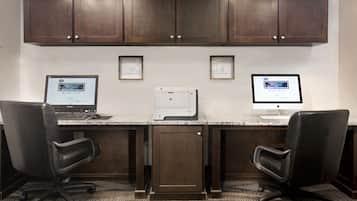 A workspace with two desks, two office chairs, a printer, and a cabinet above.
