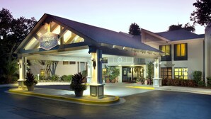 Un Hampton Inn con un área exterior cubierta, plantas en macetas y una entrada bien iluminada.
