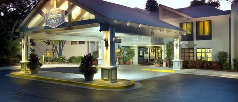 A Hampton Inn with a covered outdoor area, potted plants, and a well-lit entrance.