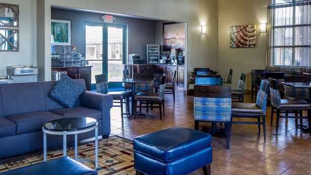 A spacious lobby with a sofa, chairs, a coffee station, and a view of the street.