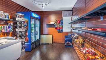 A snack bar with a Pepsi refrigerator, shelves with snacks, and a display of hats.