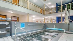 Un área de piscina interior de varios niveles, con un tobogán visible, un tendedero para toallas y un tablón de anuncios.