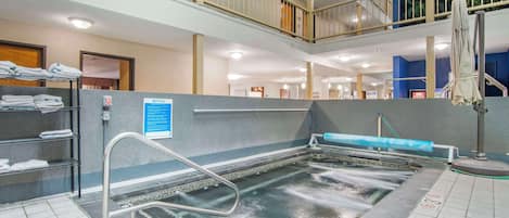 Un área de piscina interior de varios niveles, con un tobogán visible, un tendedero para toallas y un tablón de anuncios.