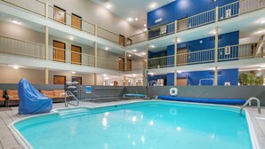 Un área de piscina interior con varios niveles, una piscina cristalina, múltiples balcones y una zona de estar cubierta.