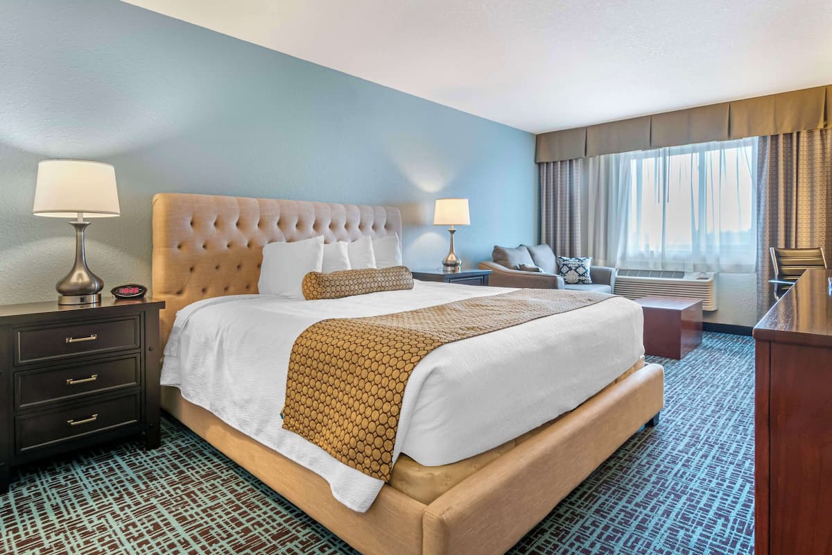 A hotel room with a large bed, two bedside tables with lamps, a desk, and a chair.