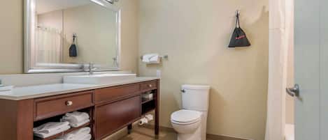 A bathroom with a sink, mirror, toilet, and towel rack.