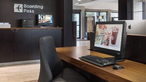 Una moderna recepción de hotel con un monitor de computadora que muestra un anuncio de Starbucks, un teclado y una silla.