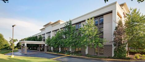 A modern building with a covered entrance, multiple windows, and well-maintained landscaping.