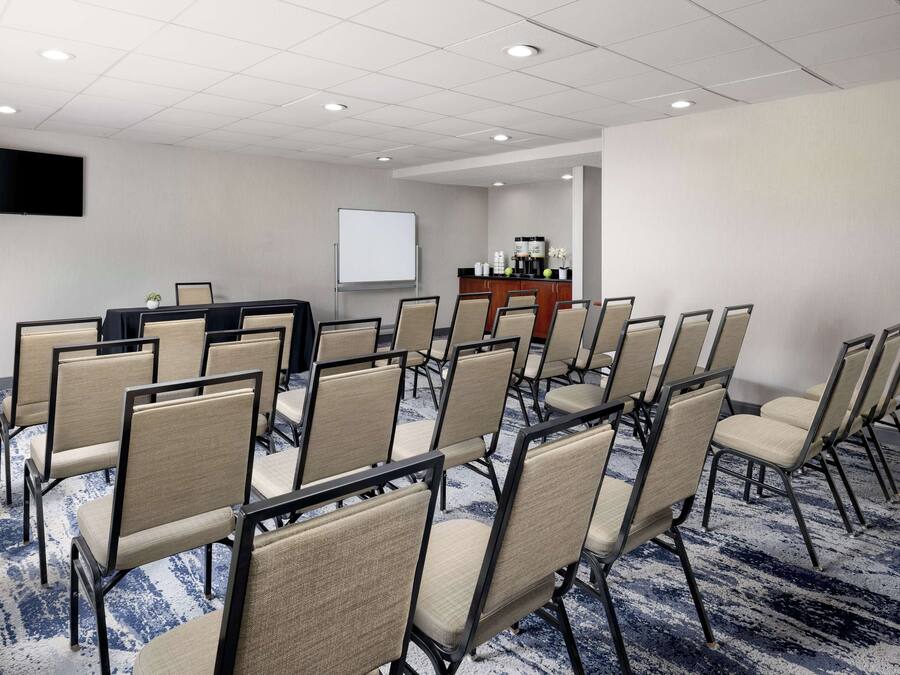 A conference room with rows of chairs, a projector screen, and a coffee station.