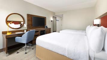 Une chambre d’hôtel avec un grand lit, un bureau avec une chaise, une télévision et un miroir.