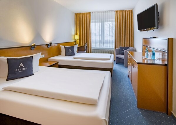 A hotel room with two beds, a desk, a chair, a TV, and a window with curtains. - Aspire Frankfurt Airport, Trademark Collection by Wyndham (Ruesselsheim)