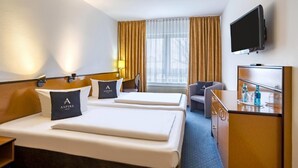 A hotel room with two beds, a desk, a chair, a TV, and a window with curtains. - Aspire Frankfurt Airport, Trademark Collection by Wyndham (Ruesselsheim)