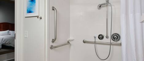 A bathroom with a shower, grab bars, and a towel rack.