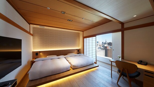 Una habitación de hotel moderna con una cama grande, un escritorio y vistas al horizonte de la ciudad.