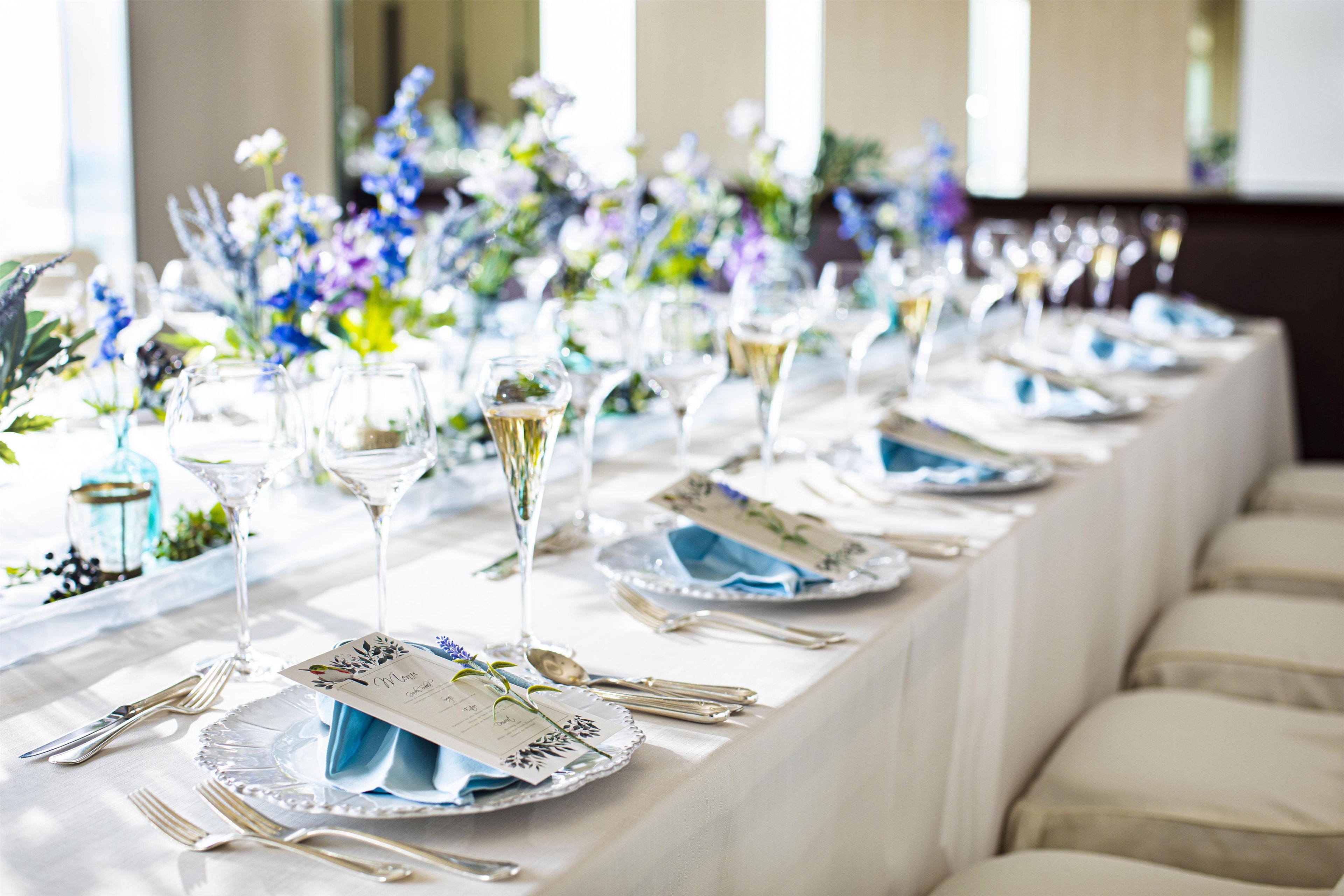 A long table set with dinnerware, glasses, and menus, indicating a formal dining event.