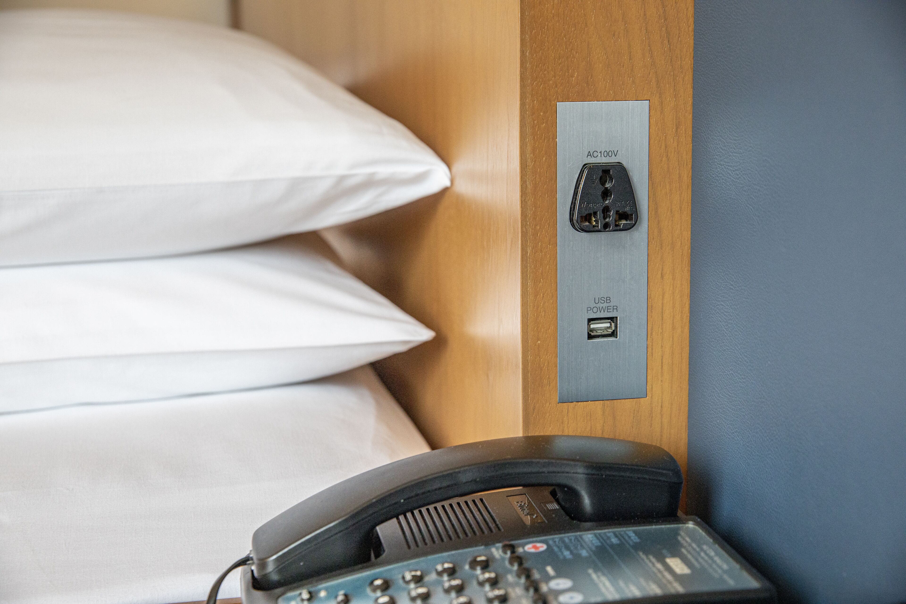 Une chambre d’hôtel équipée d’un lit, d’un téléphone sur la table de chevet et d’une prise électrique dotée d’un port USB.