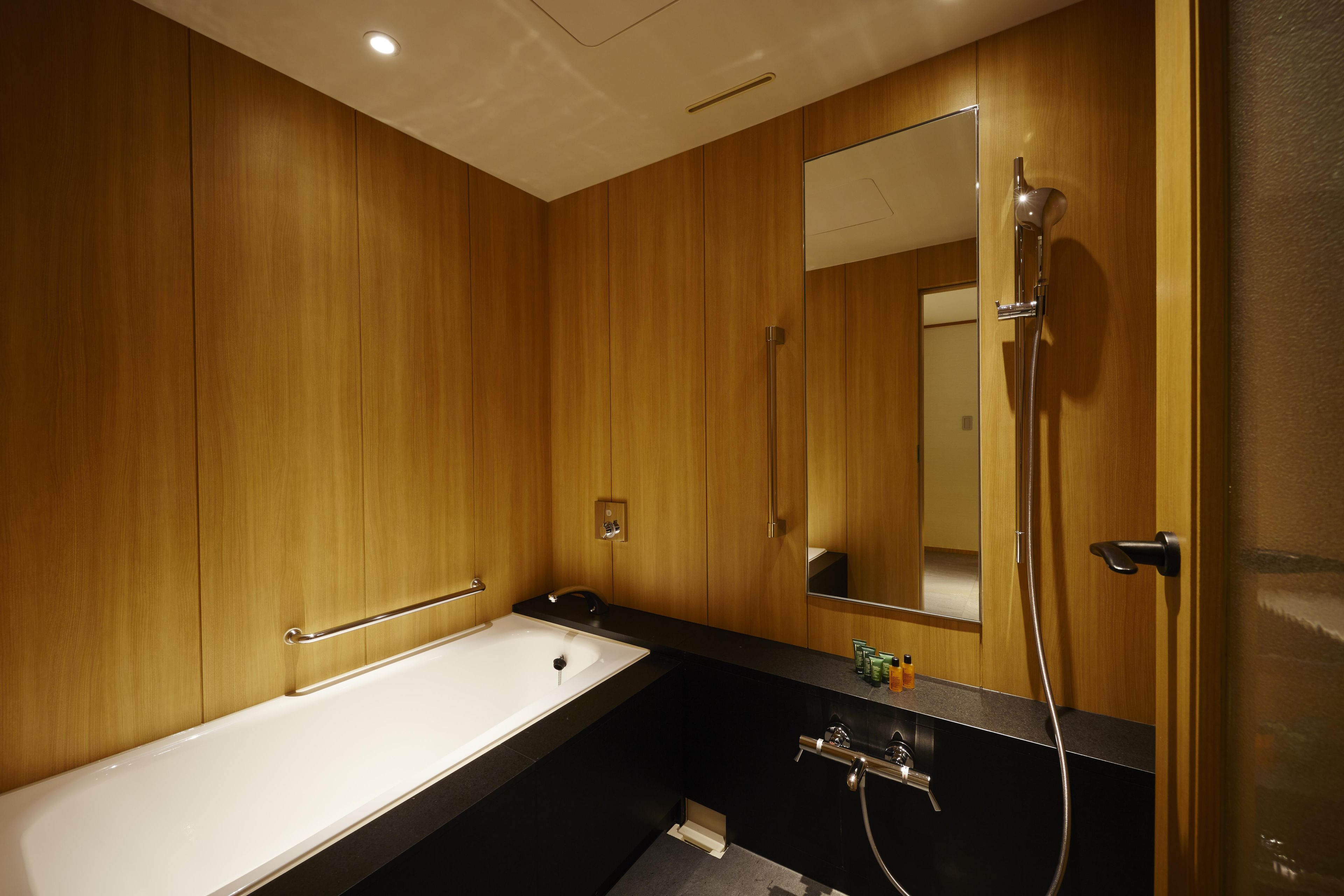 Une salle de bain avec une baignoire, un miroir et une douche.