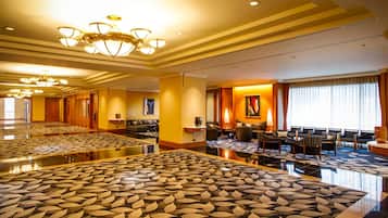 A spacious hotel lobby with a patterned carpet, multiple seating areas, and a large chandelier.