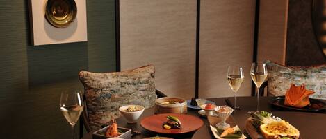 A dining table set with various dishes, glasses of wine, and a decorative pillow.
