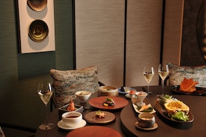 Una mesa de comedor adornada con diferentes platos, copas de vino y un cojín decorativo.