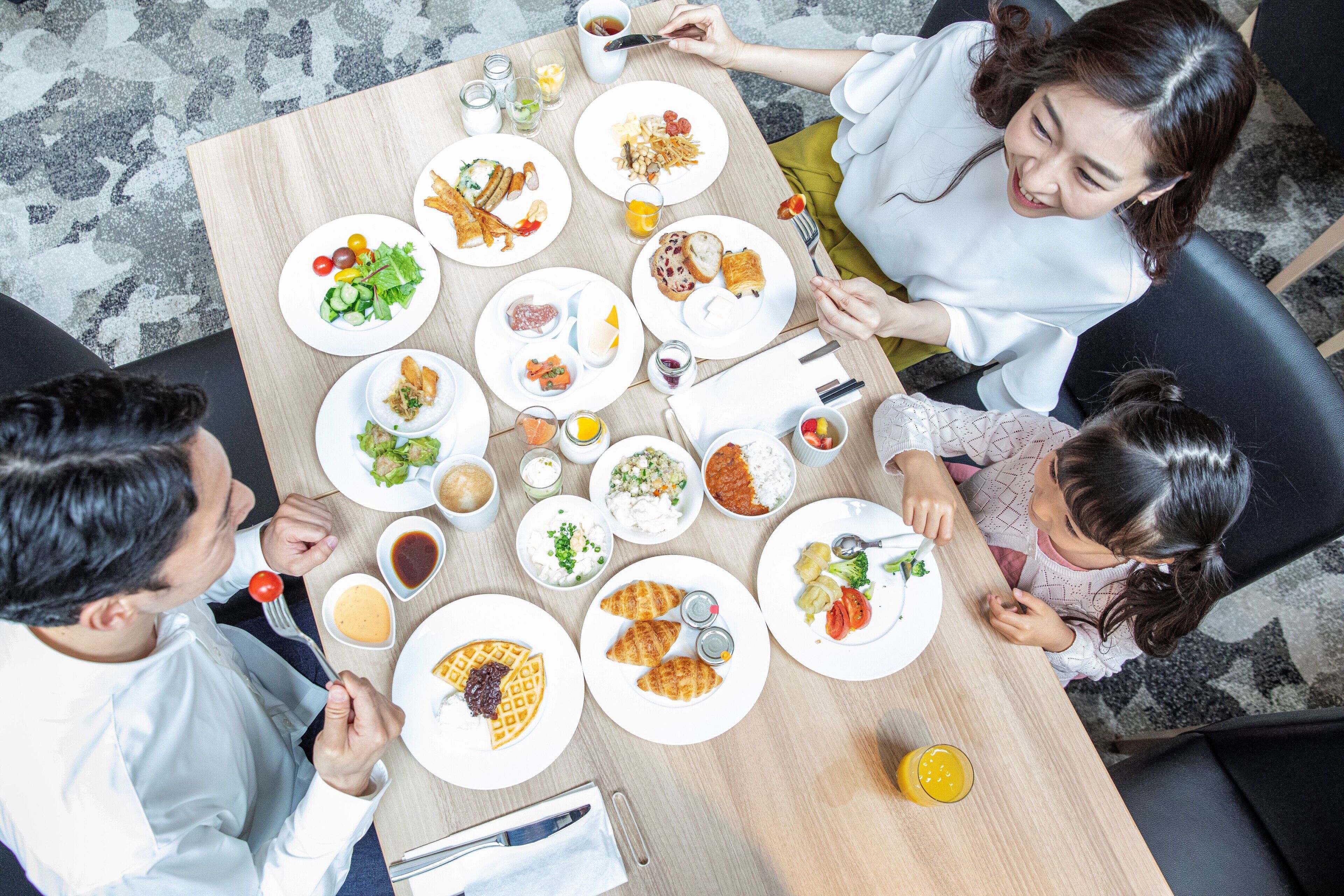 A dining table with various dishes and condiments, surrounded by people.