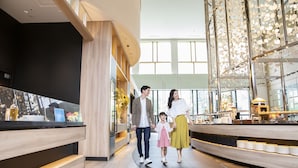 Un moderno vestíbulo de hotel con un mostrador de recepción curvo, techo alto y grandes ventanales.