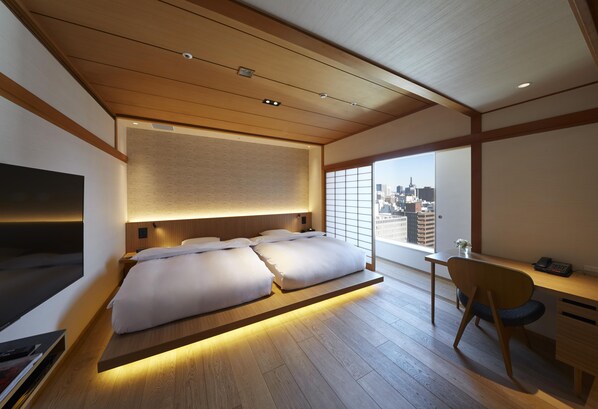 A modern hotel room with a large bed, a desk, and a view of the city skyline. - Hilton Nagoya (Nagoya)