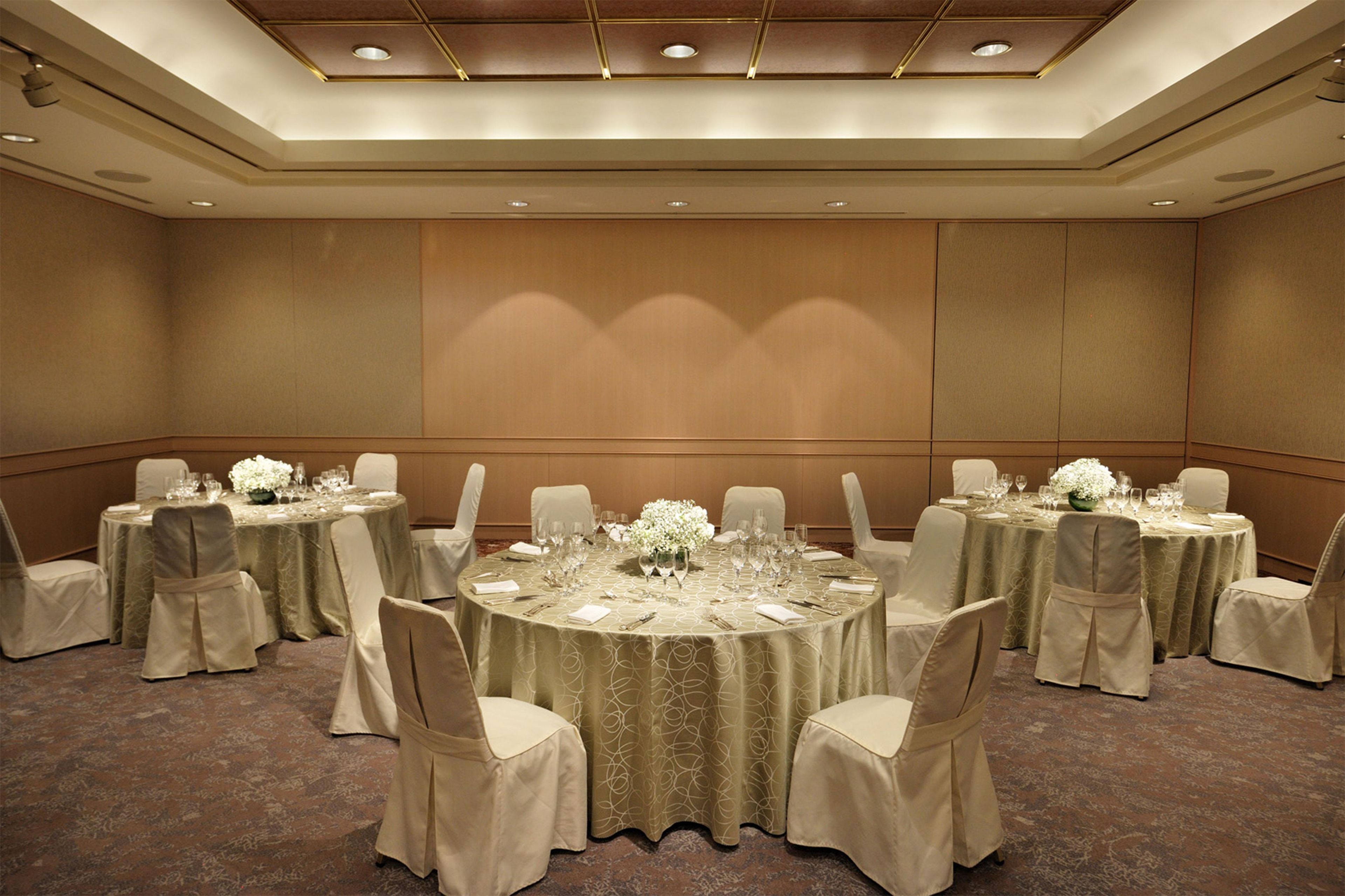 A conference room with round tables, chairs, and a carpeted floor.