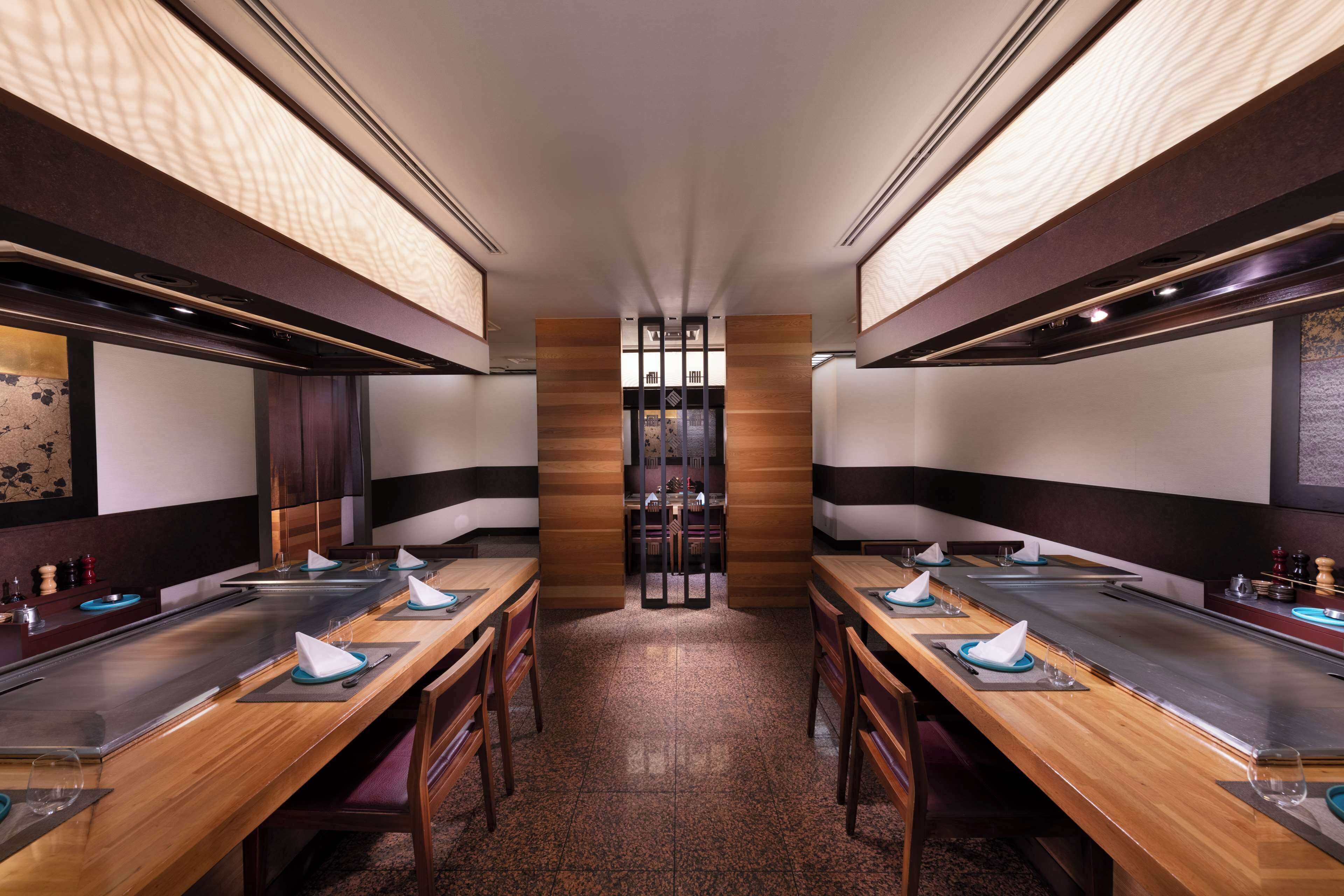 A restaurant with long wooden tables, black and white striped walls, and a central column.