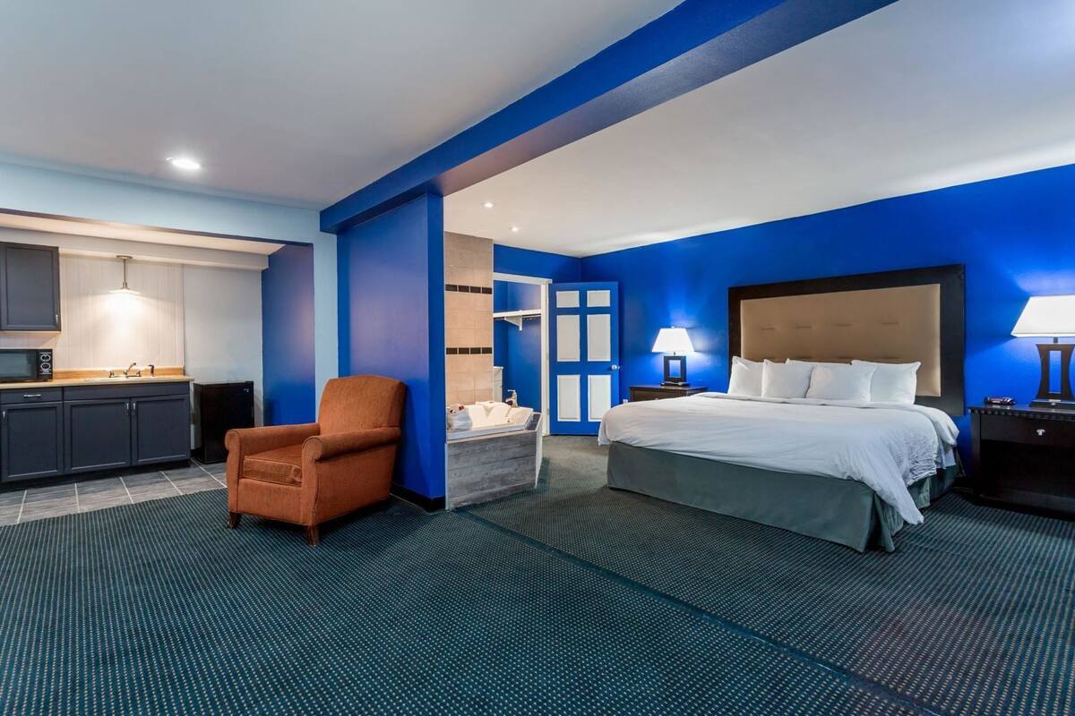 A hotel room with a bed, a chair, a desk, and a bathroom.