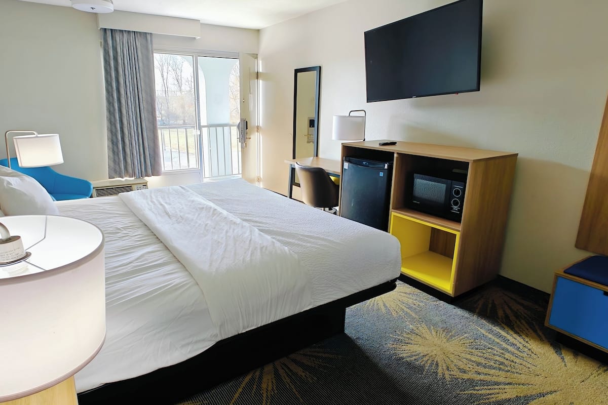 A hotel room with a bed, a desk, a television, and a wardrobe.