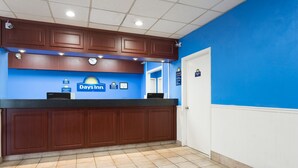 Une salle d’attente avec un mur bleu, un comptoir d’accueil et une horloge.