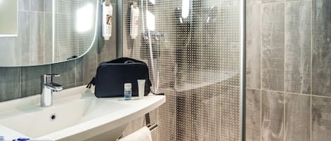 A modern bathroom with a large mirror, a sink, and a shower area.