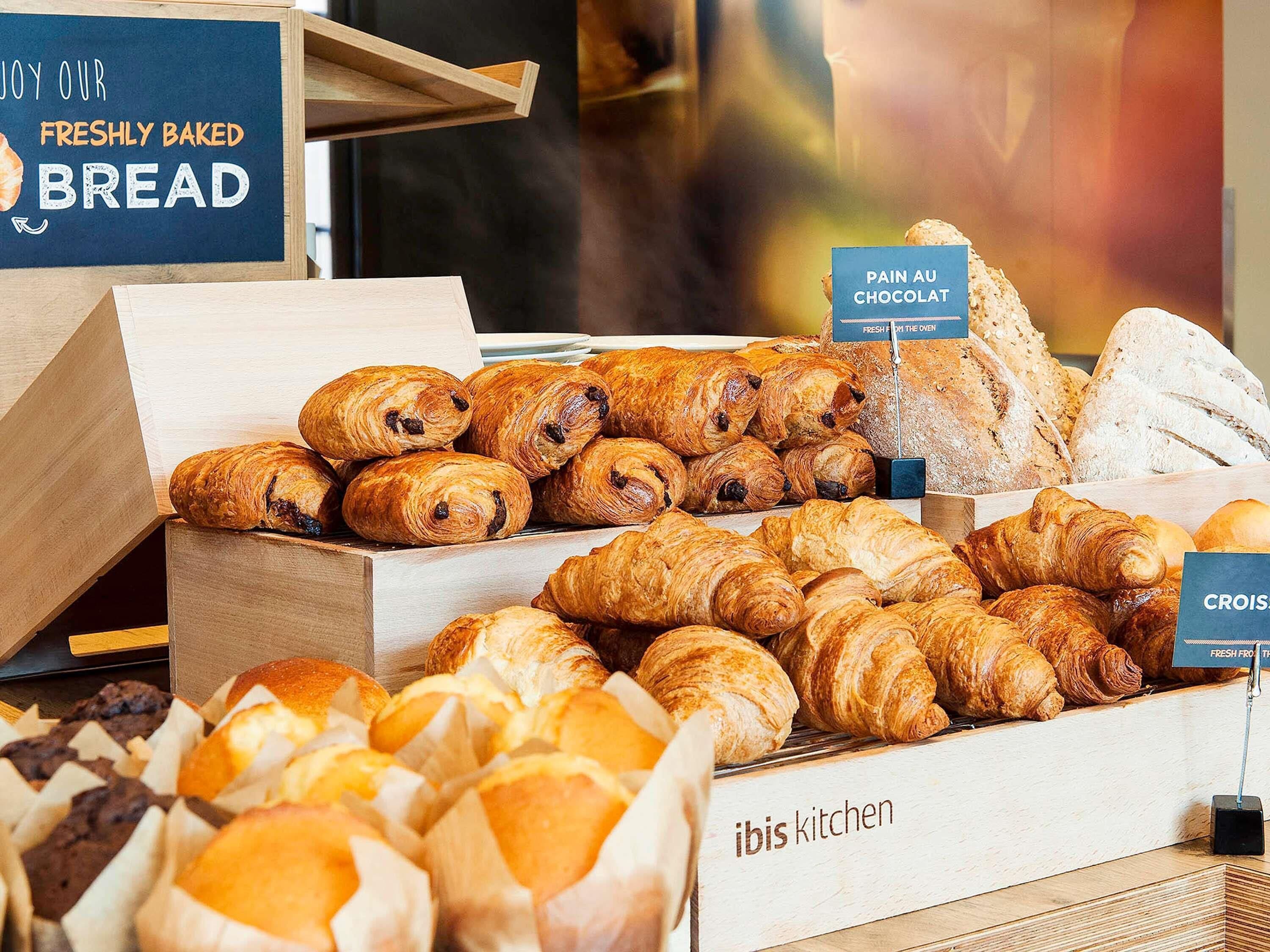 Een bakkerijvitrine met diverse gebakken producten, waaronder croissants en brood.