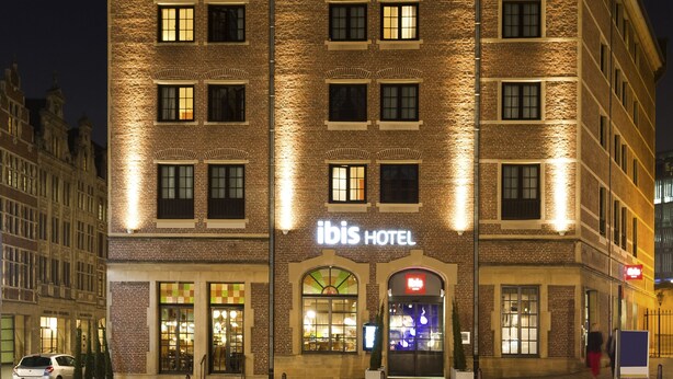 Een hotel met een bakstenen gevel, meerdere ramen en een bord waarop 