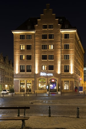 Een hotel met een bakstenen gevel, meerdere ramen en een bord waarop 