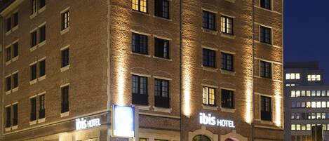 A hotel with a brick facade, multiple windows, and outdoor seating area with chairs and tables.